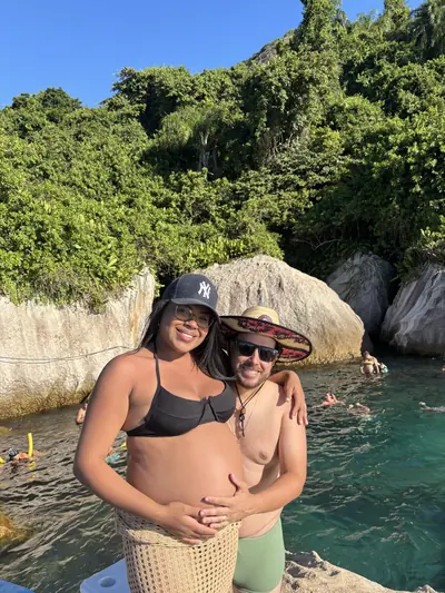 Casal na água junto ao costão de pedras.