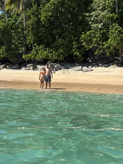 Casal na beira da ilha, visto de dentro do mar.