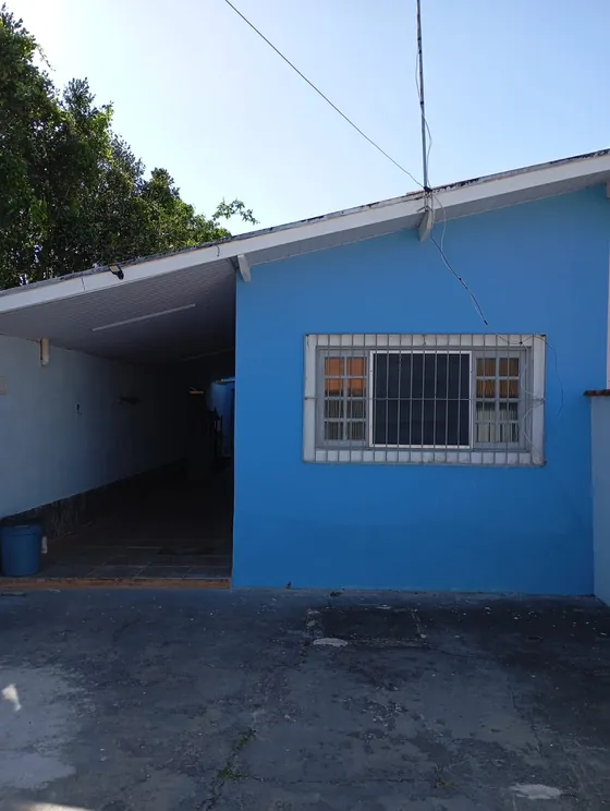 Lateral da casa azul, com a garagem coberta.