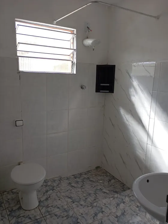 Banheiro com chuveiro e janela basculante.