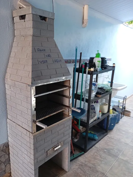 Churrasqueira em torre, com estante de apoio ao lado.
