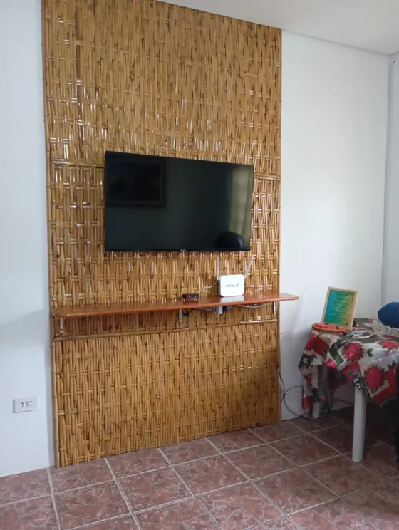Sala com televisão em painel de madeira ripada.