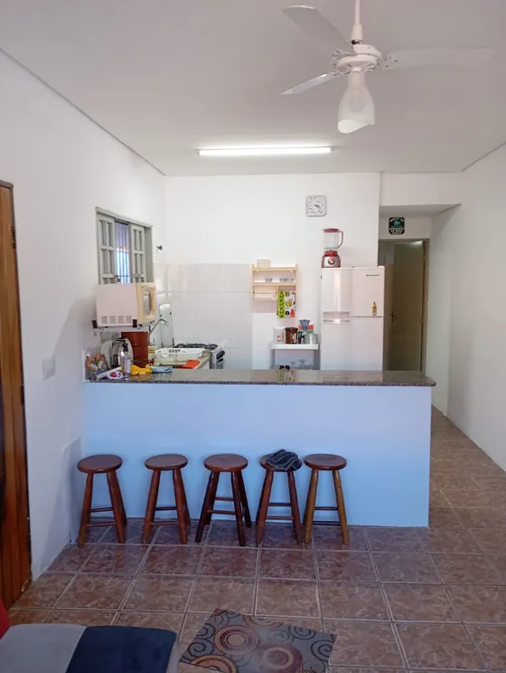 Cozinha ampla com bancada e banquinhos de madeira.