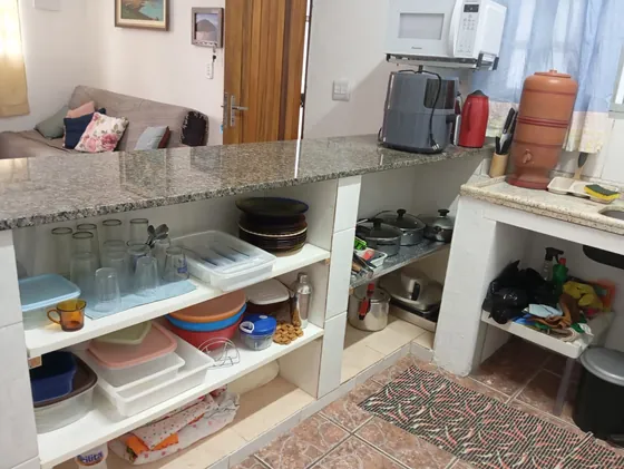 Sala integrada à cozinha, com bancada de granito e prateleiras abertas.