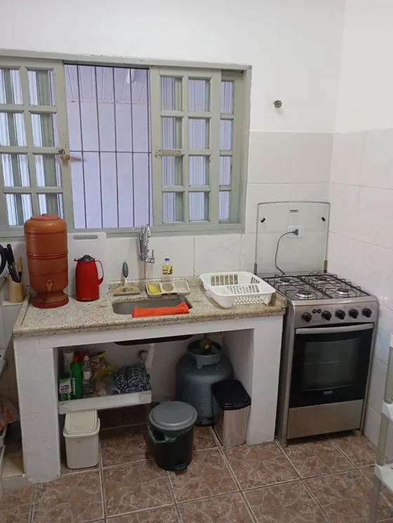 Cozinha com fogão, pia e janela para fora.