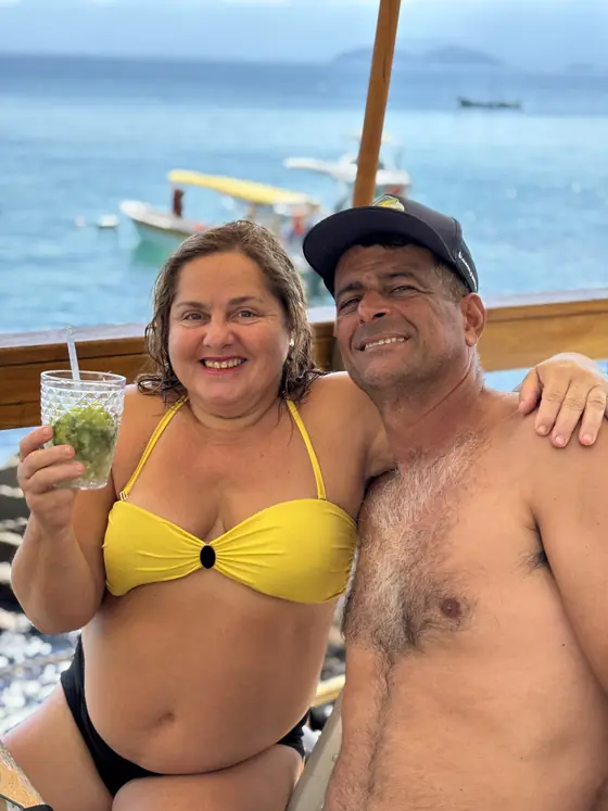 Casal no barco durante a parada, com o mar atrás.