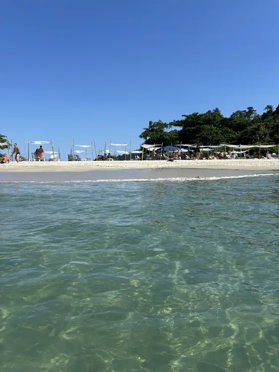 A praia d’As Ilhas com guarda-sóis e quiosques, vista de dentro da água.