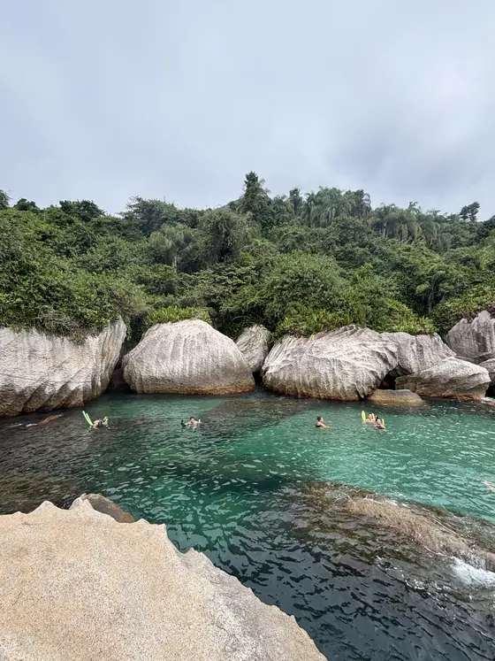 Piscina natural do Montão do Trigo vista de cima do costão, com banhistas na água.