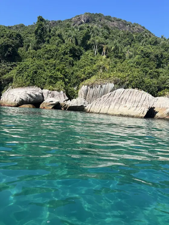 Blocos de pedra branca na beira da ilha, com a água verde-esmeralda em volta.