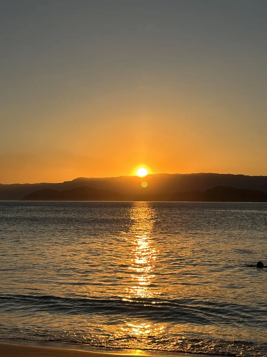 O sol saindo do mar, com o reflexo dourado atravessando a água.