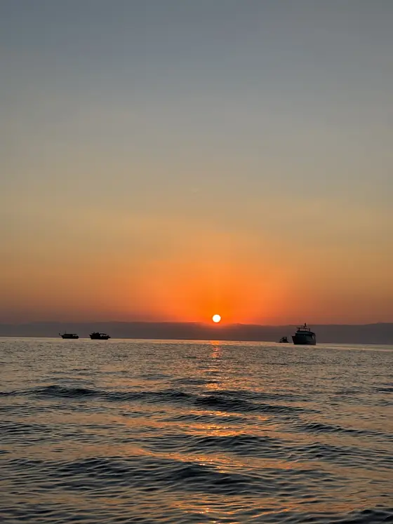 O sol aparecendo na linha do horizonte, visto do mar aberto.