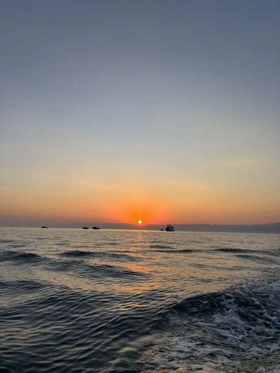 O sol já acima do horizonte, visto de dentro do barco.